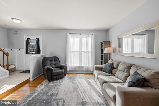 living area with stairway, wood finished floors, and baseboards