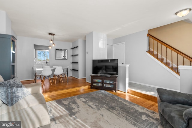 living room featuring stairs, baseboards, and wood-type flooring