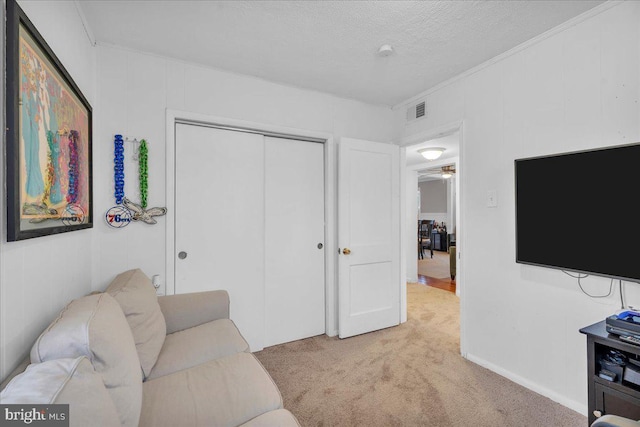 carpeted living area with a textured ceiling and visible vents