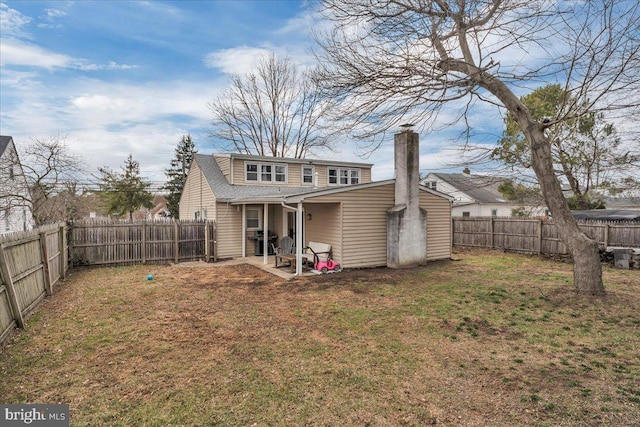 rear view of house featuring a shingled roof, a lawn, a chimney, and a fenced backyard