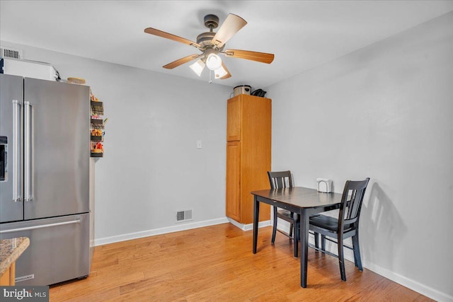 dining area featuring a ceiling fan, light wood-type flooring, and baseboards