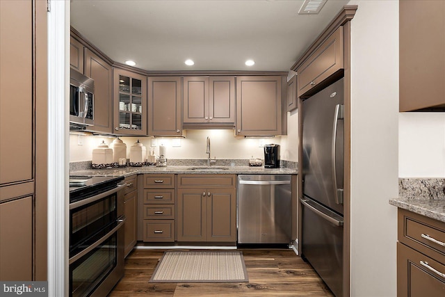 kitchen featuring a sink, dark wood-type flooring, light stone counters, and stainless steel appliances