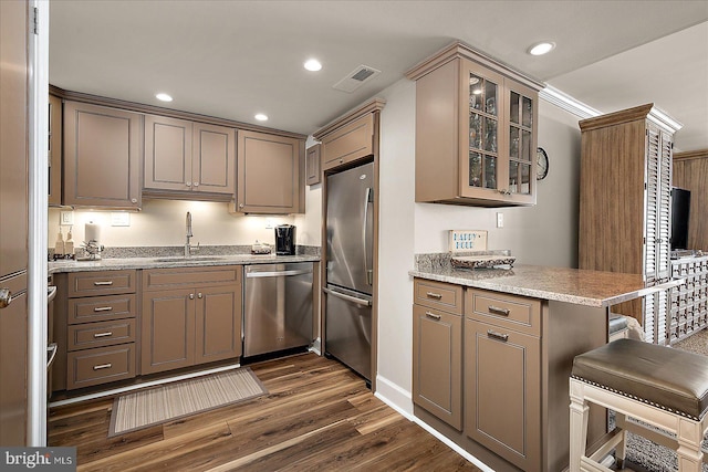 kitchen with visible vents, dark wood-type flooring, a sink, appliances with stainless steel finishes, and glass insert cabinets