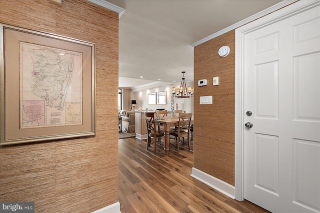 entrance foyer with baseboards, crown molding, an inviting chandelier, and wood finished floors