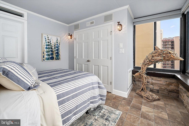 bedroom featuring visible vents, a closet, crown molding, and stone finish floor