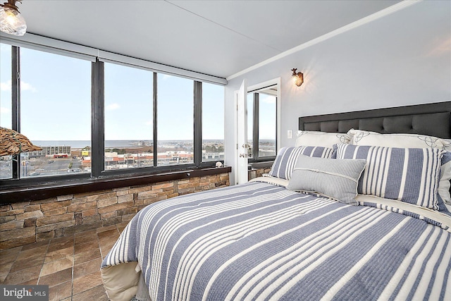 bedroom with stone finish flooring and crown molding