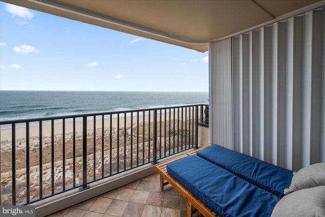 balcony with a water view and a view of the beach