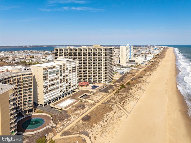 drone / aerial view featuring a water view, a city view, and a beach view