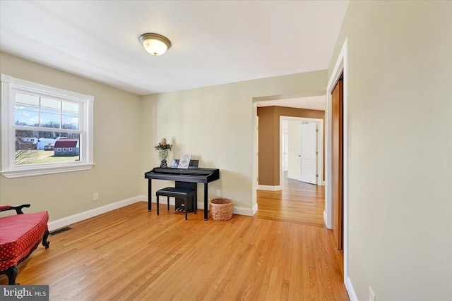 sitting room with visible vents, light wood-style floors, and baseboards