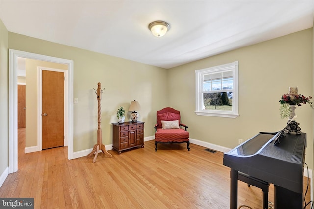 living area featuring visible vents, baseboards, and light wood-style floors