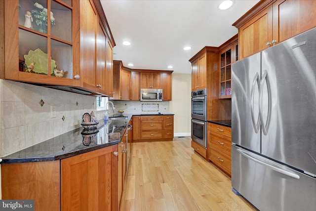 kitchen with light wood-type flooring, brown cabinets, backsplash, and stainless steel appliances