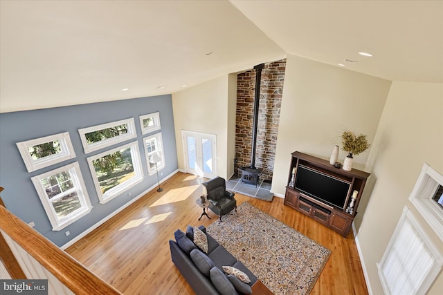 living room featuring baseboards, lofted ceiling, recessed lighting, a wood stove, and wood finished floors