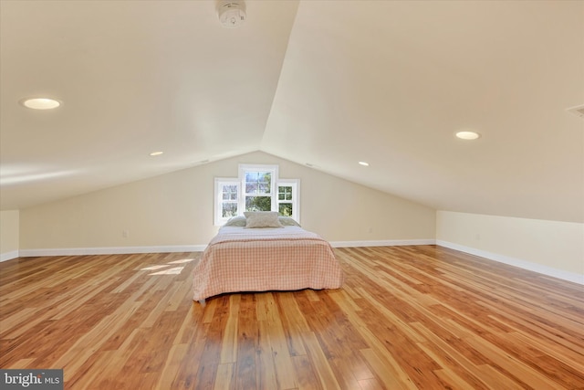 unfurnished bedroom featuring visible vents, light wood-style flooring, baseboards, and vaulted ceiling