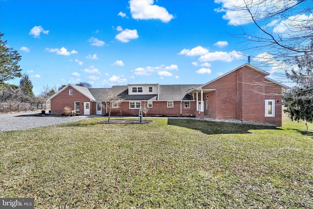 rear view of house with brick siding and a yard