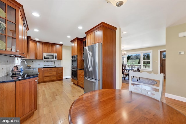 kitchen featuring light wood-style floors, tasteful backsplash, appliances with stainless steel finishes, and a sink