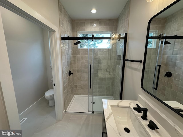 bathroom featuring toilet, a stall shower, vanity, baseboards, and tile patterned floors