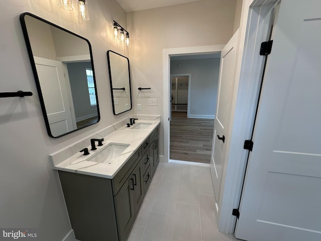 bathroom with double vanity, tile patterned flooring, a sink, and baseboards