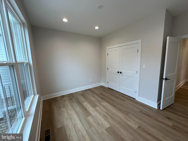 unfurnished bedroom featuring recessed lighting, wood finished floors, visible vents, and baseboards