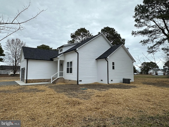 view of home's exterior featuring central AC unit, crawl space, a shingled roof, and a lawn