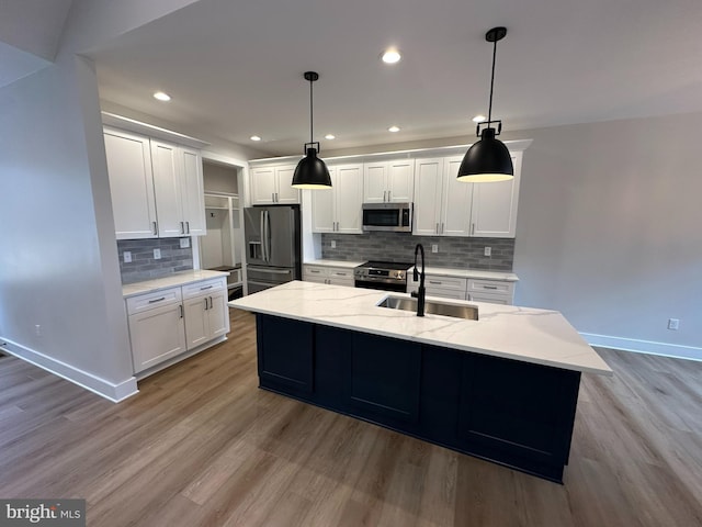 kitchen with baseboards, appliances with stainless steel finishes, light wood-style floors, white cabinetry, and a sink