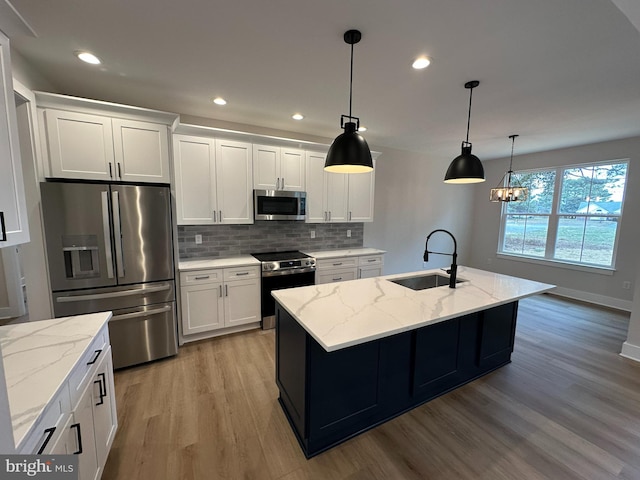 kitchen featuring a sink, white cabinets, appliances with stainless steel finishes, light wood-type flooring, and tasteful backsplash