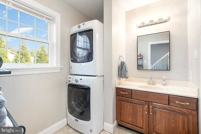 washroom with light tile patterned floors, stacked washer and dryer, laundry area, a sink, and baseboards