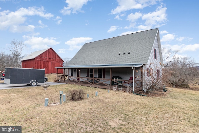 rear view of property with a yard, roof with shingles, an outdoor structure, and a barn