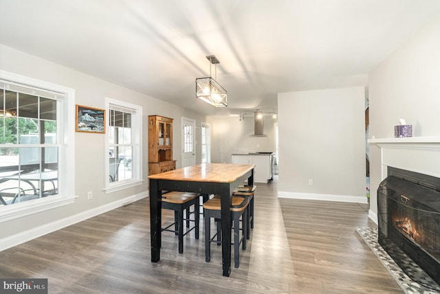 dining room with a fireplace with flush hearth, dark wood finished floors, and baseboards