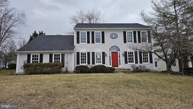 colonial house featuring a front lawn and a shingled roof