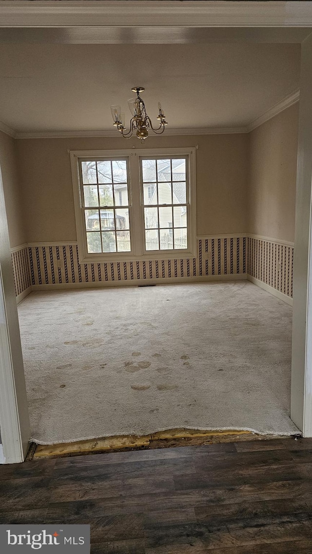 spare room featuring a notable chandelier, carpet, and crown molding