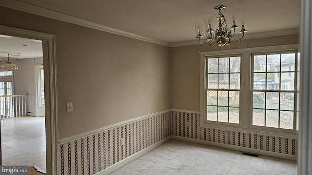 unfurnished dining area with a chandelier, visible vents, wainscoting, carpet, and crown molding