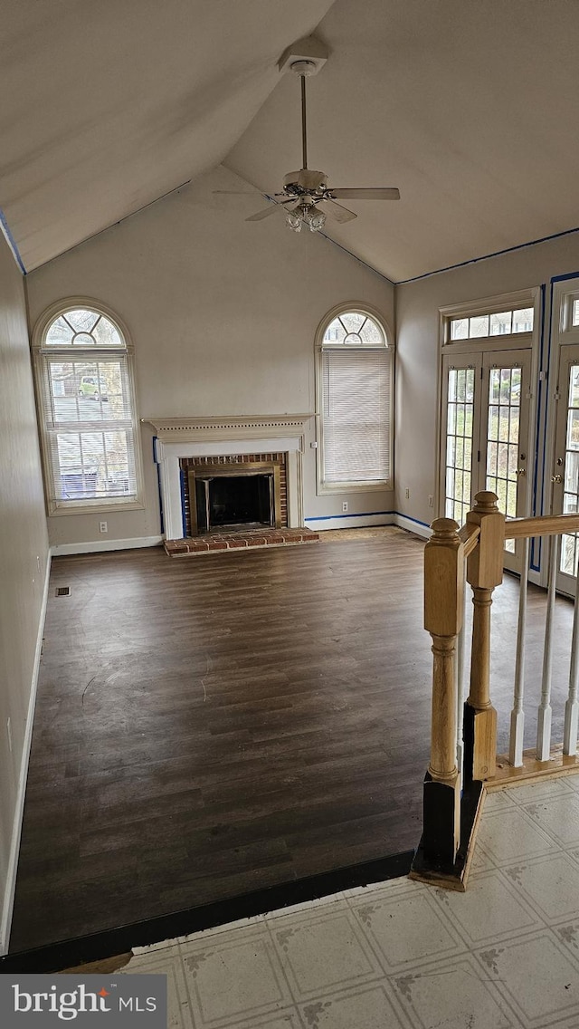 unfurnished living room with vaulted ceiling, a fireplace, wood finished floors, and visible vents