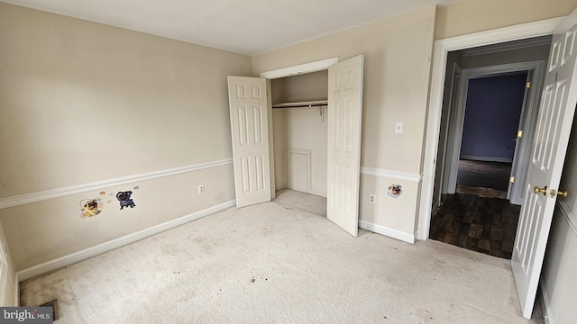 unfurnished bedroom featuring carpet, baseboards, and a closet