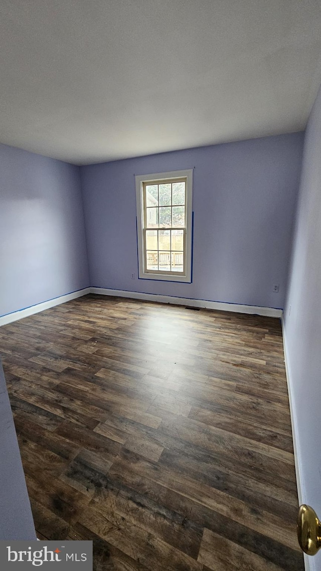 empty room with dark wood-type flooring and baseboards