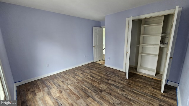 unfurnished bedroom with baseboards, dark wood finished floors, and a closet