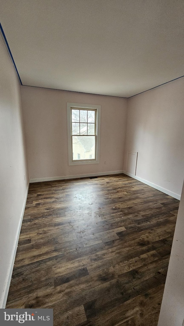 spare room with dark wood-style floors and baseboards