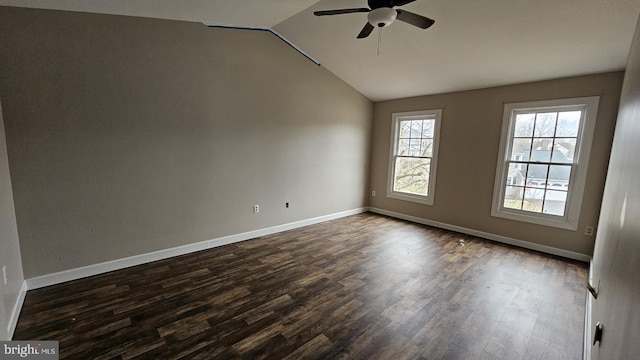 unfurnished room with dark wood-style floors, vaulted ceiling, and baseboards