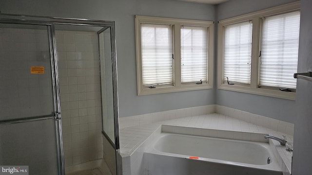 bathroom featuring a garden tub and a shower stall