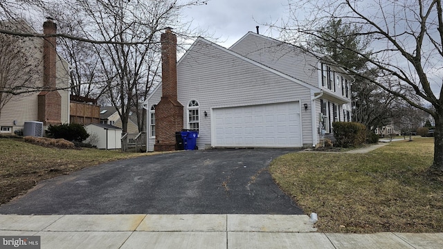 view of home's exterior with driveway, central AC unit, a lawn, and an attached garage