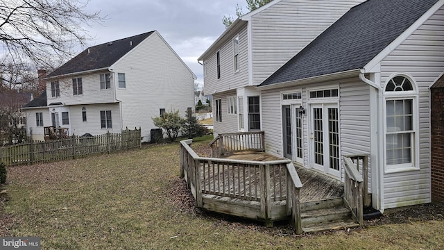 back of property featuring a shingled roof, fence, and a deck