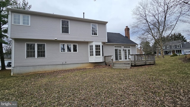 back of house featuring a wooden deck, a chimney, a lawn, and french doors