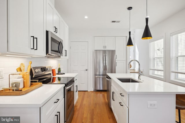 kitchen featuring visible vents, light wood-style flooring, a sink, tasteful backsplash, and stainless steel appliances