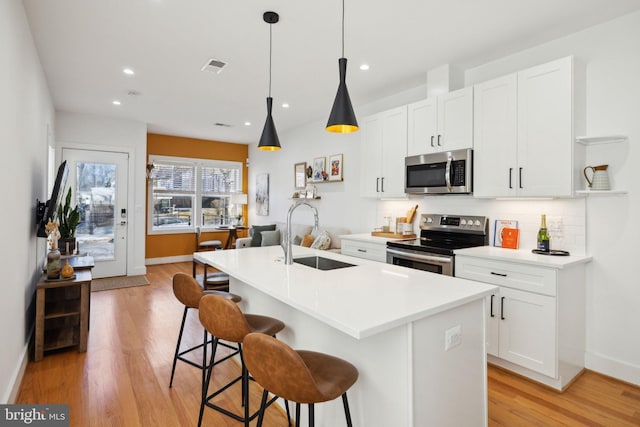 kitchen featuring visible vents, backsplash, light wood-style flooring, stainless steel appliances, and a sink