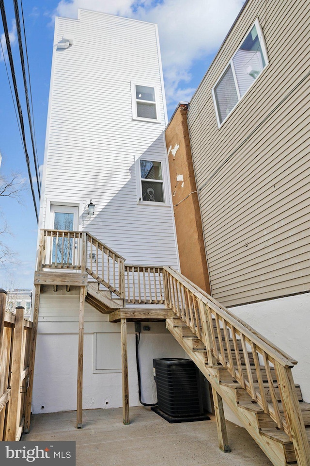 rear view of property featuring stairs and central AC unit