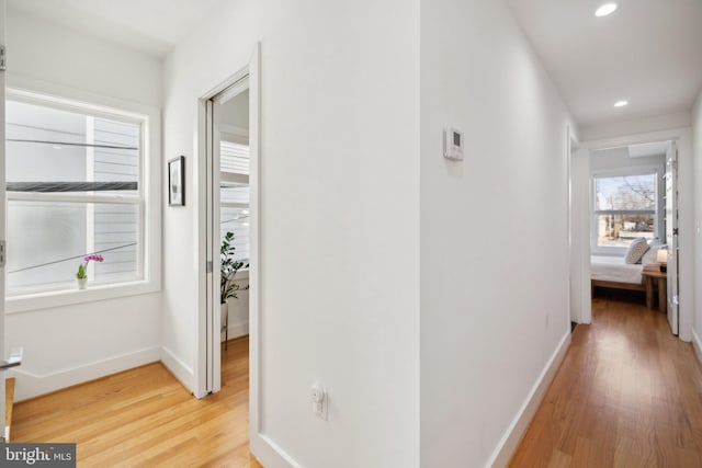 hallway with recessed lighting, light wood-style floors, and baseboards