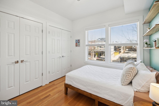 bedroom featuring light wood-style floors and multiple closets