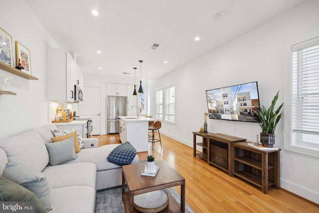 living area featuring recessed lighting, visible vents, and light wood-type flooring