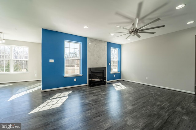 unfurnished living room featuring a large fireplace, ceiling fan, baseboards, recessed lighting, and wood finished floors