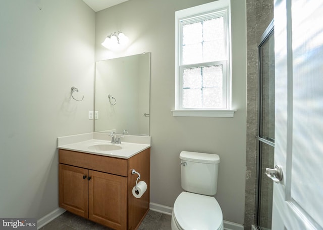 full bath featuring a tile shower, toilet, vanity, and baseboards