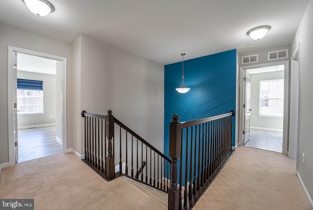 hallway with carpet flooring, an upstairs landing, and visible vents